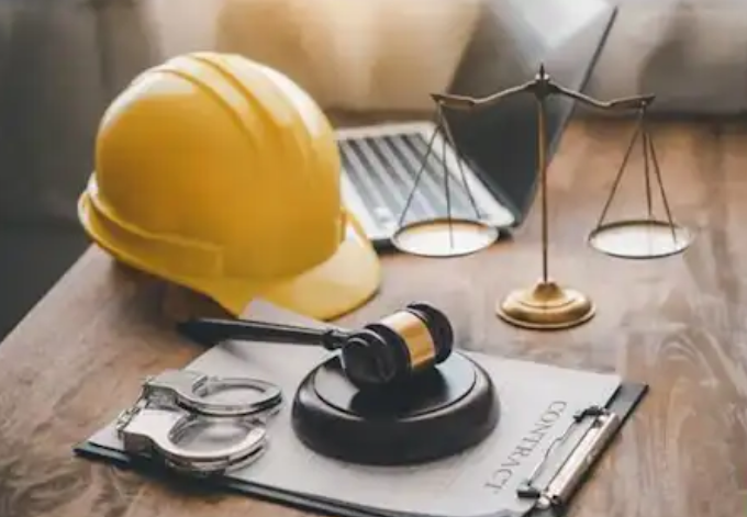 Casco de protección, balanza y mazo sobre un contrato de trabajo